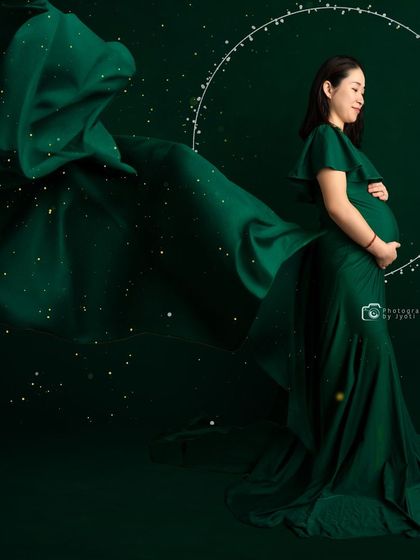 A creative portrait using a flowing green gown and digital effects to create a magical, starry night scene.