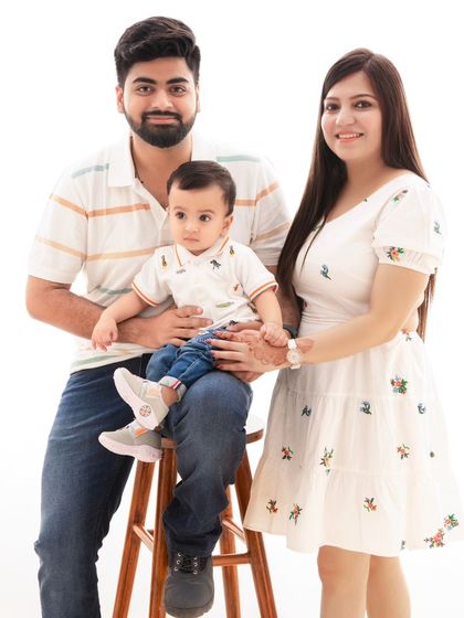 A classic family portrait against a clean white background. The simple elegance of this style allows the family's connection to be the star.