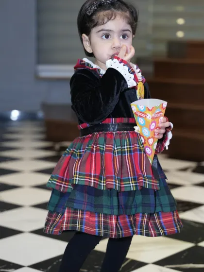 A little girl enjoys a cone of popcorn, one of the many kid-friendly snacks we offer.