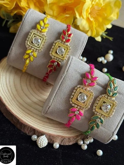 Elegant single rakhis with a leaf motif and a central stone. The vibrant enamel colors on the leaves make these designs stand out.