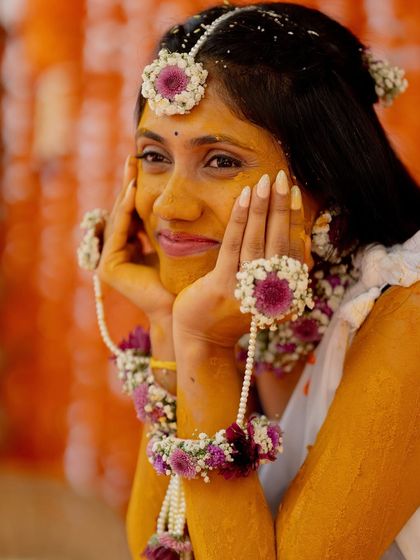 A close-up of the bride's beautiful smile and her floral jewelry during the Haldi ceremony. The delicate, custom-made flower accessories perfectly complement the traditional event.