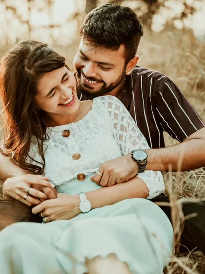 A beautiful, candid moment of a couple laughing together in a field. This joyful portrait perfectly captures the happiness and lightheartedness of their relationship.