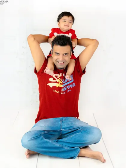 A fun and playful father-son moment, with the happy baby sitting on his dad's shoulders. This is a timeless pose that shows their connection.