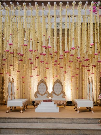 A closer look at the mandap seating, featuring ornate white and gold chairs set against a backdrop of thousands of delicate floral strings. The design exudes a sense of quiet luxury and grace.
