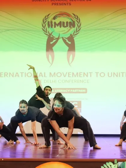 The dance troupe in a dynamic, grounded pose during our stage performance. This showcases the blend of contemporary and athletic movement we incorporate into our group choreographies.