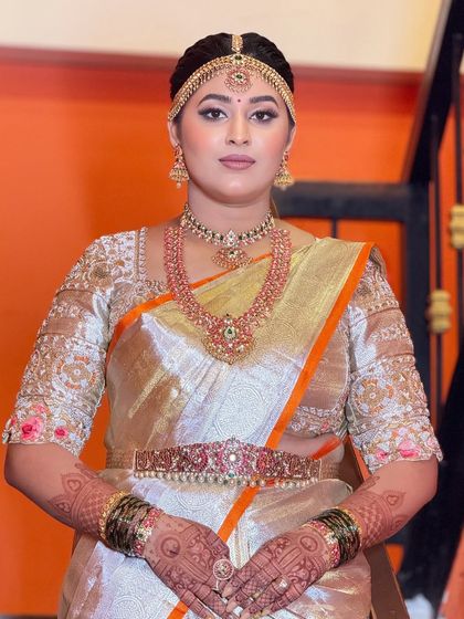A classic portrait of the bride, showcasing her full wedding attire. The makeup is perfectly balanced to complement her jewelry and saree.