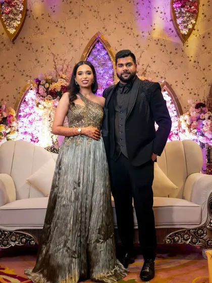 A formal portrait of the couple on their engagement stage, framed by the elaborate floral decor.