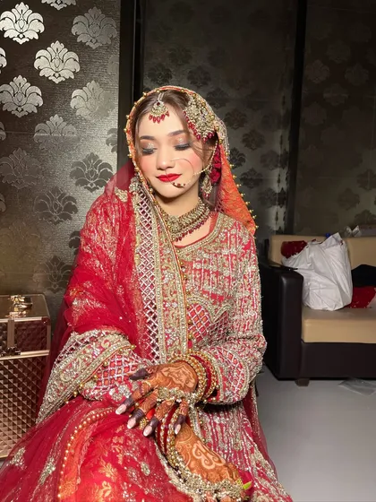 A quiet moment before the ceremony. This image shows the bride in her full Nikah attire, with soft, shimmery eye makeup and a classic red lip.
