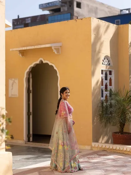 The bride walks through the sunlit courtyard of the palace, her colorful lehenga a beautiful contrast to the warm yellow walls.