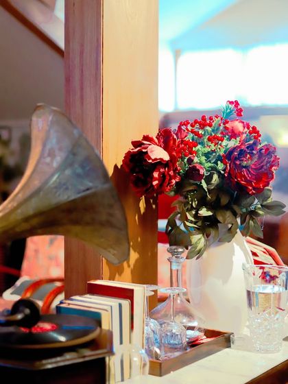 A vintage-style vignette with a gramophone and a bouquet of red flowers, blending nostalgia with holiday spirit.