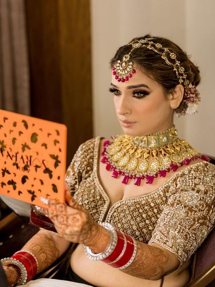 A bride looking in the mirror, admiring her royal look complete with our heavy bridal jewellery.