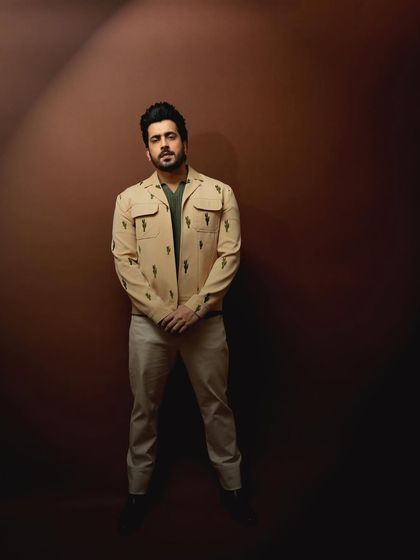 A full-length shot of the dress, with the flowing ribbon adding a sense of motion against the clean studio background.