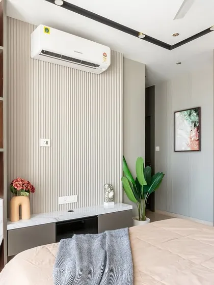 This bedroom blends clean modern lines with cozy, earthy tones and elegant copper accents. Ribbed wall panels create visual interest, while carefully chosen decor and a splash of greenery add warmth and character.