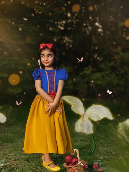 Posed like a true princess in an enchanted garden, this little girl looks out with a curious expression. The glowing butterflies and soft light add to the fairytale atmosphere.