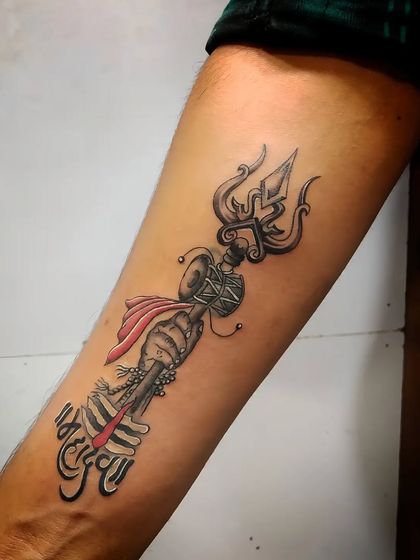 This is a custom design of a Trishul with "Mahadev" written in Hindi script. The red cloth adds a touch of color and makes the design stand out.