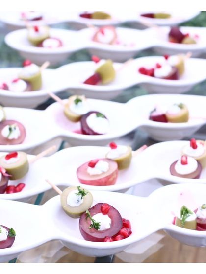 An artful arrangement of fruit and cream cheese bites on a wavy platter. The use of fresh plums and pomegranate seeds adds a jewel toned elegance to the display.