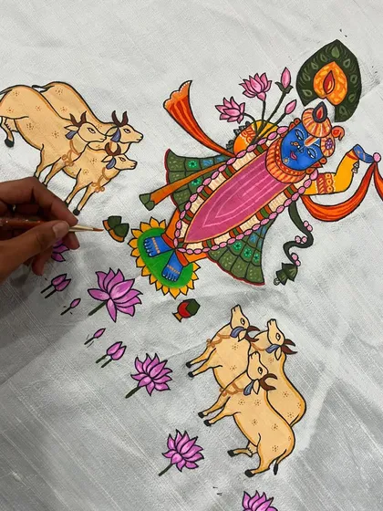 A work-in-progress shot of a beautiful Pichwai-style painting on fabric. I am carefully detailing Lord Shrinathji, surrounded by cows and lotuses, using a vibrant, traditional color palette.