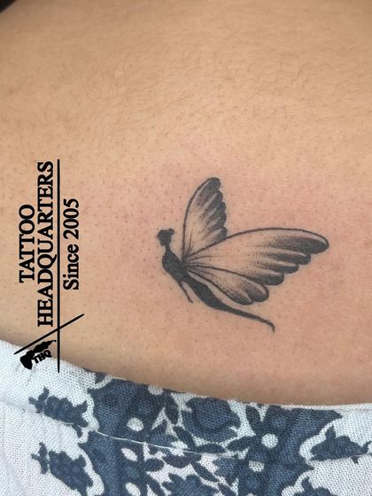 A delicate butterfly tattoo with shading that gives it a realistic, three-dimensional look.