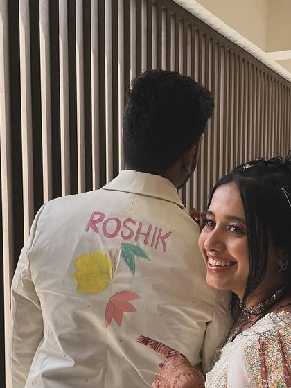 It's all in the details. The back of the groom's jacket features his name, "Roshik," painted in a playful font, adding a fun, personalized touch to his custom carnival outfit.