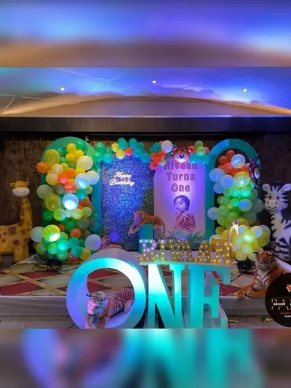 A jungle-themed first birthday with large, inflatable animal props. This setup features light-up "ONE" letters, a themed backdrop, and a colorful balloon arrangement.