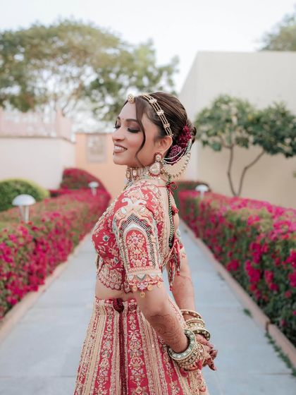 A beautiful portrait of the bride in her red lehenga. Her elegant updo is adorned with a maathapatti, completing her regal look.