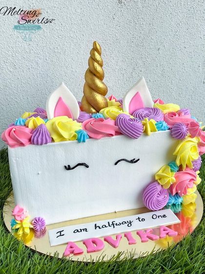 Celebrating a half birthday is a fun milestone. This half-cake is designed as a colorful unicorn, complete with a golden horn and a mane of rainbow whipped cream swirls.