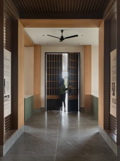 A view through the lobby corridor, framed by wood-paneled columns and tribute displays. The design uses strong lines and natural light to guide visitors through the space.