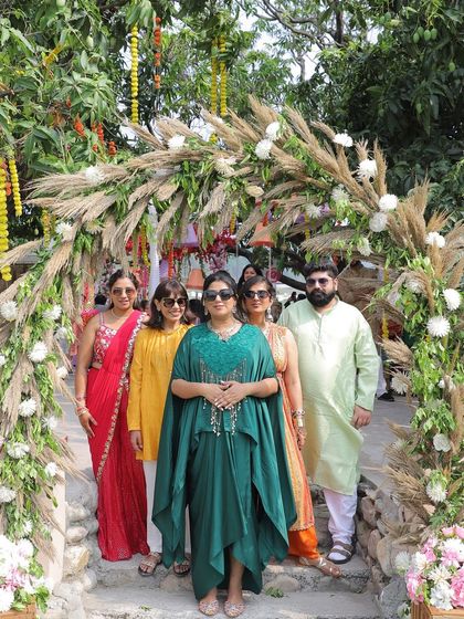 A group photo of the bride and her family under a beautiful floral and pampas grass arch at the mehendi.