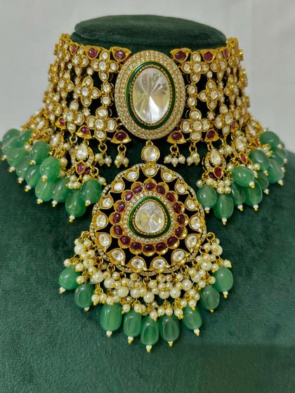A close-up of the heavy bridal choker with a large pendant. The intricate Kundan work and green bead drops are clearly visible in this shot.