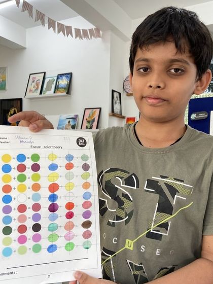 This student is showing his completed color theory worksheet. We teach core art principles, like how to mix primary and secondary colors, through practical and easy to understand exercises.