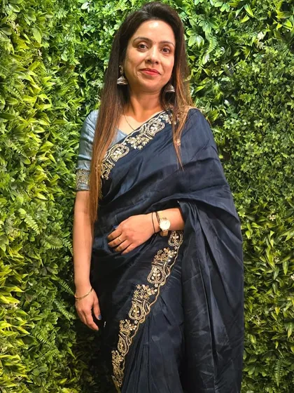 A client posing against a green wall in the deep teal blue saree, a versatile piece for both day and evening events.