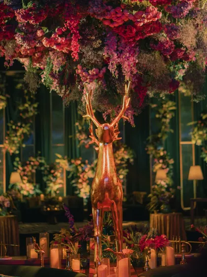 A golden deer stands majestically under a cloud of jewel-toned flowers at the emerald-themed Sangeet, adding to the enchanted forest atmosphere.