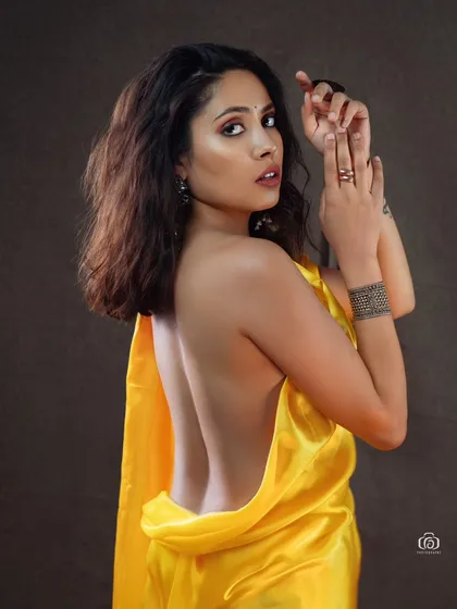 A back-focused shot showcasing the draping of the yellow satin fabric. This angle provides a different perspective on the outfit and highlights the model's pose.