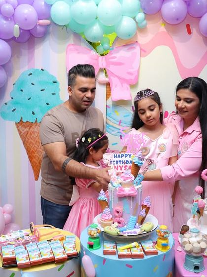 The cake-cutting ceremony at the Candyland party, featuring an elaborate, candy-topped cake and a table full of sweet treats.