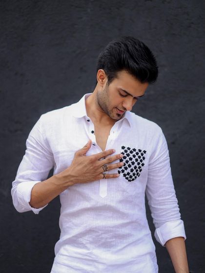 A model looking down at the checkered pocket detail on his white kurta. This shot emphasizes the unique design element that sets my work apart.