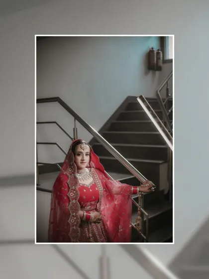 A portrait of Shreya on a staircase, her red lehenga flowing, creating a classic and elegant composition.
