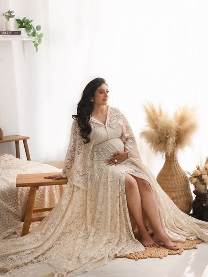 This portrait captures the elegance of the lace gown and the thoughtful expression of the mom-to-be, surrounded by the soft, warm elements of the boho studio.