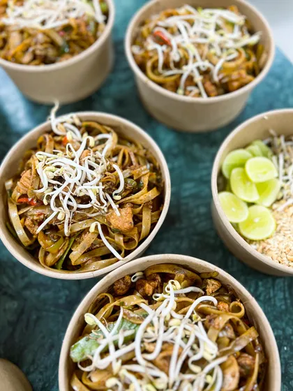 Our Pad Thai noodles, topped with fresh bean sprouts and lime wedges. We pack the crushed peanuts separately to keep them crunchy.