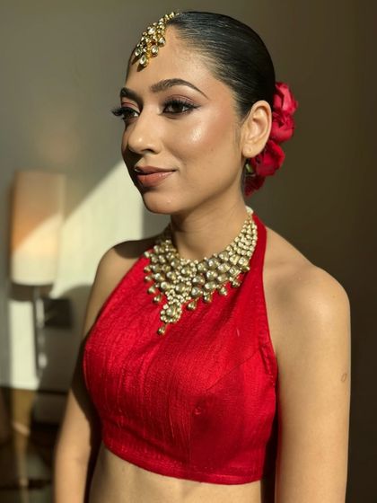 A classic and bold look. The sleek, low bun adorned with red roses is the epitome of timeless elegance, perfectly paired with a sharp winged liner.