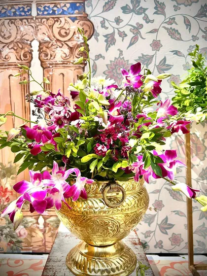 A beautiful floral arrangement in a traditional brass urn, part of a South Indian themed Mehendi decor.