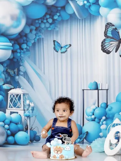 A messy but happy cake smash moment from a blue butterfly-themed first birthday party.