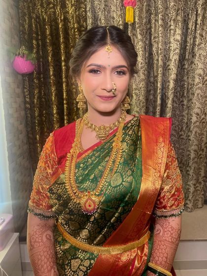 A close-up of the bride's Puja look. The makeup is soft and traditional, with gold jewelry and a simple bindi completing the elegant style.