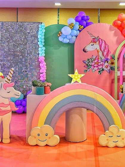 A modern and colorful unicorn party setup with a silver sequin wall, a rainbow prop, and a large unicorn cutout.