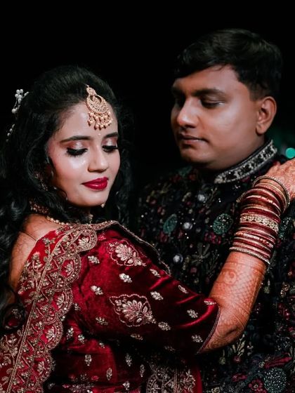 A classic pose showing the couple's elegant reception outfits and the bride's intricate henna design.
