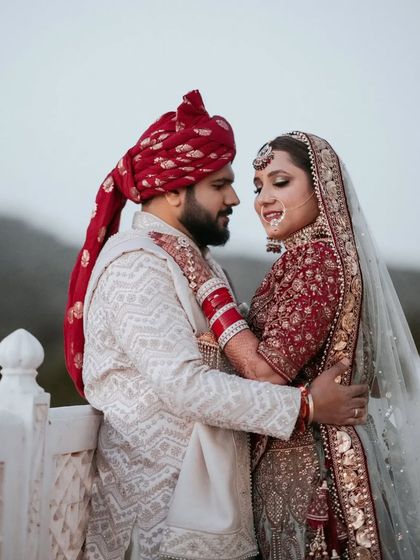 An intimate portrait of Sahil and Shikha against the backdrop of the Jaipur mountains. The groom's red turban complements the bride's beautiful lehenga, creating a picture of royal elegance.