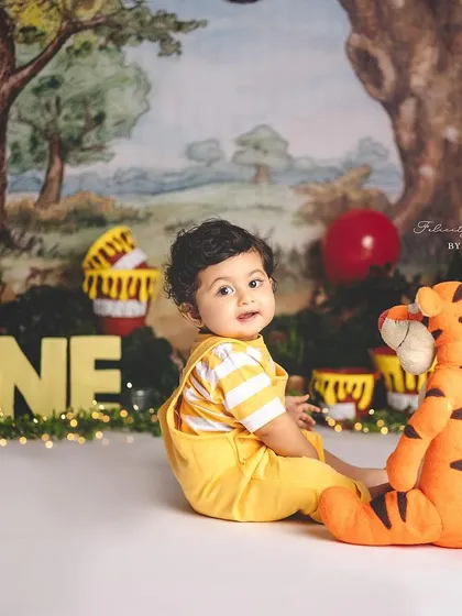A sweet moment between a boy and his Tigger toy during his first birthday photoshoot in the Hundred Acre Wood.