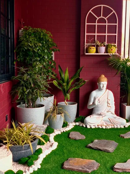 The serene expression of the Buddha statue brings a sense of peace and mindfulness to this colorful balcony garden.