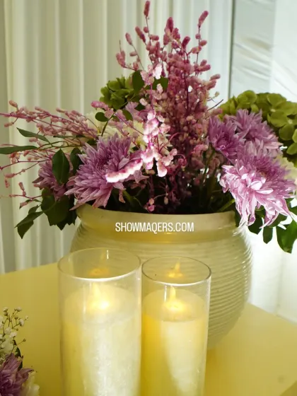 A beautiful centerpiece with purple and white flowers in a ceramic vase, complemented by the soft light of candles.