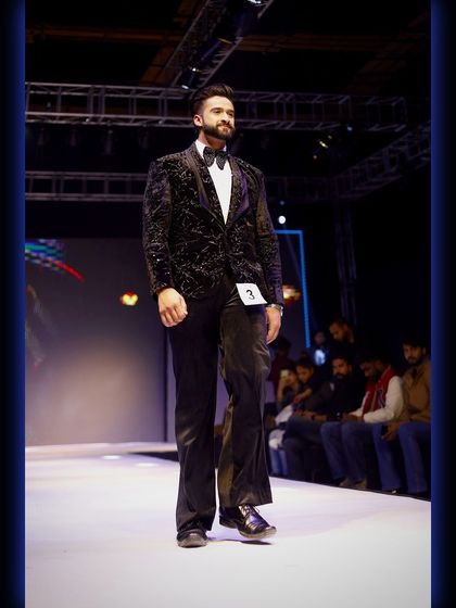 A model commands the runway in our black velvet tuxedo with a subtle, elegant pattern. This piece combines classic texture with a modern design.