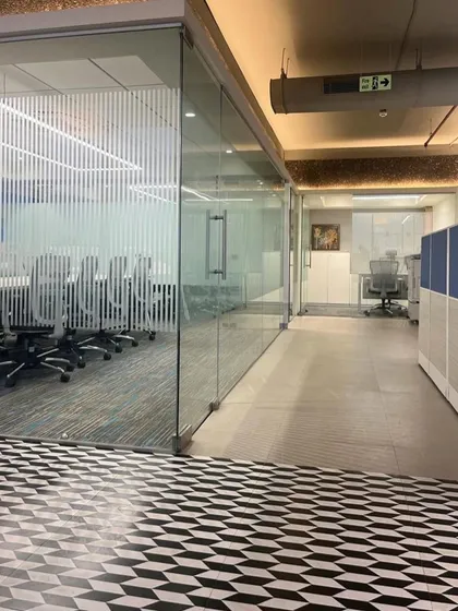 The Umicore office features a bold, geometric-patterned floor that leads to a glass-enclosed conference room. This design choice adds visual energy and clearly delineates different functional zones.
